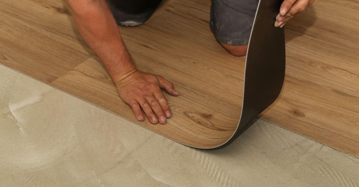 man laying vinyl flooring
