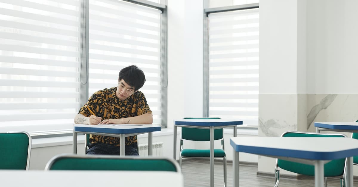 man sitting at desk in classroom taking exam to become a property manager